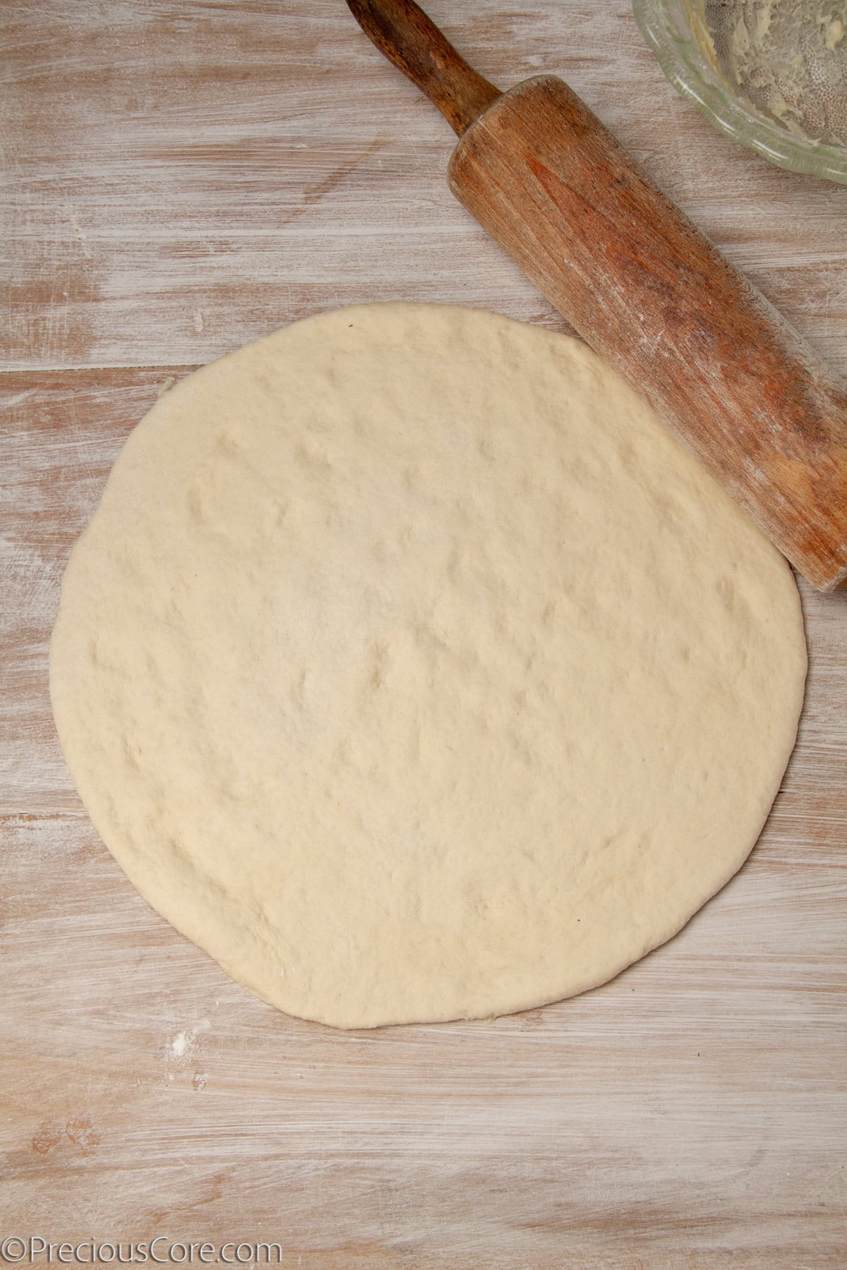 Pizza dough rolled out to form a large circle.