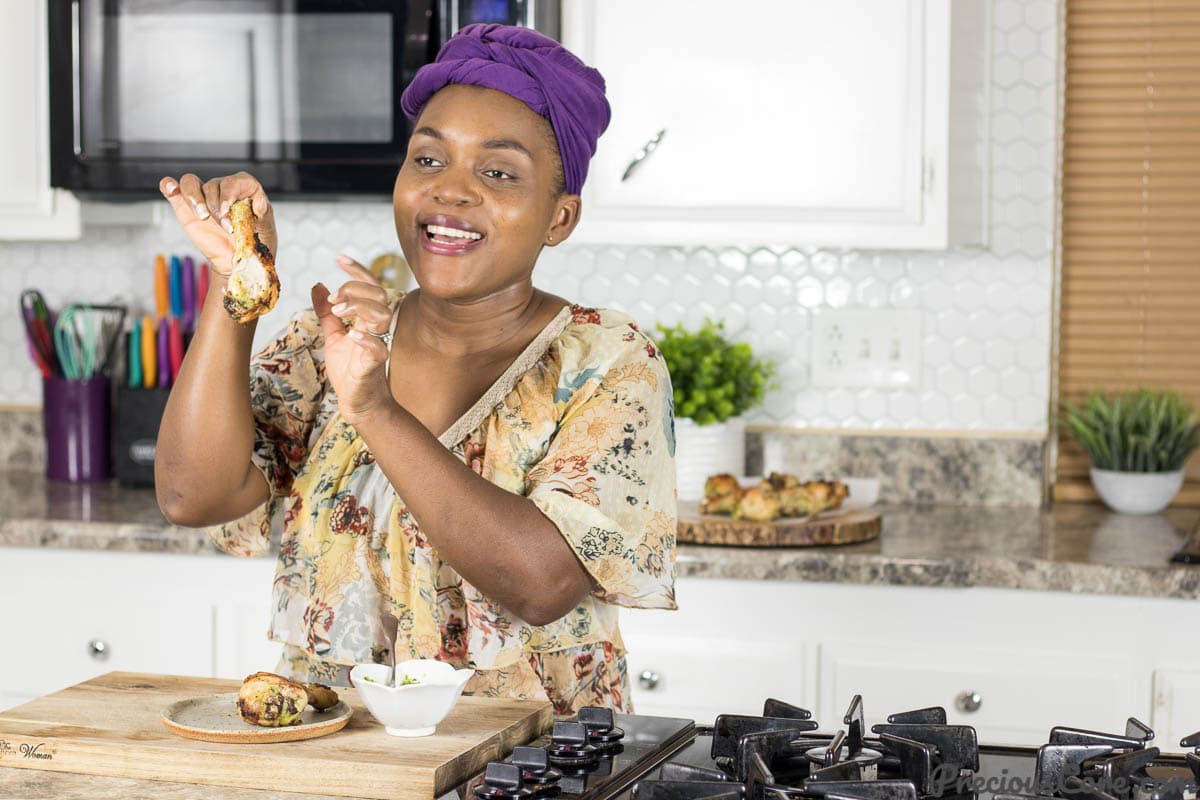Woman in kitchen holding a piece of chicken