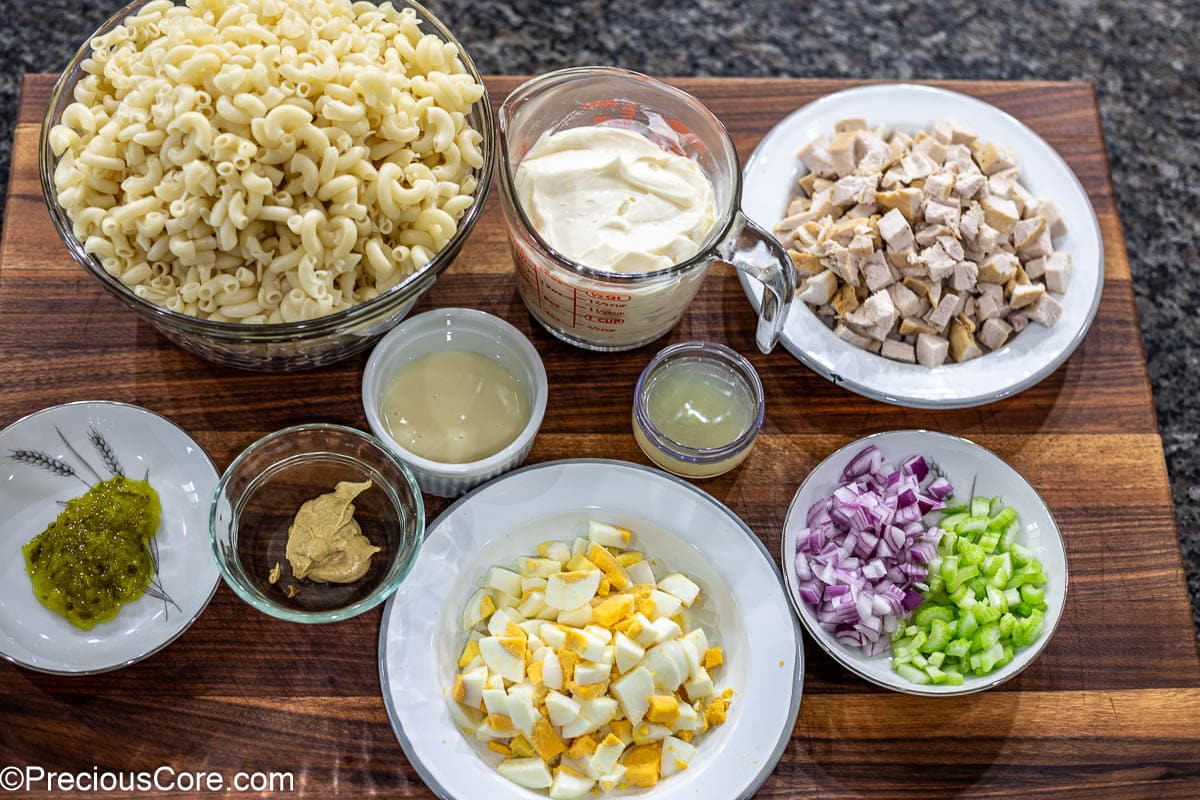 Ingredients for macaroni salad laid out on a chopping board.
