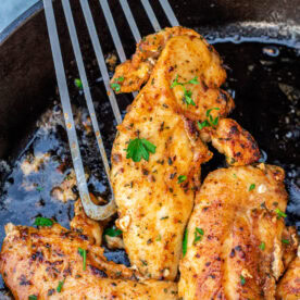 Spatula holding a cooked chicken tenderloin.