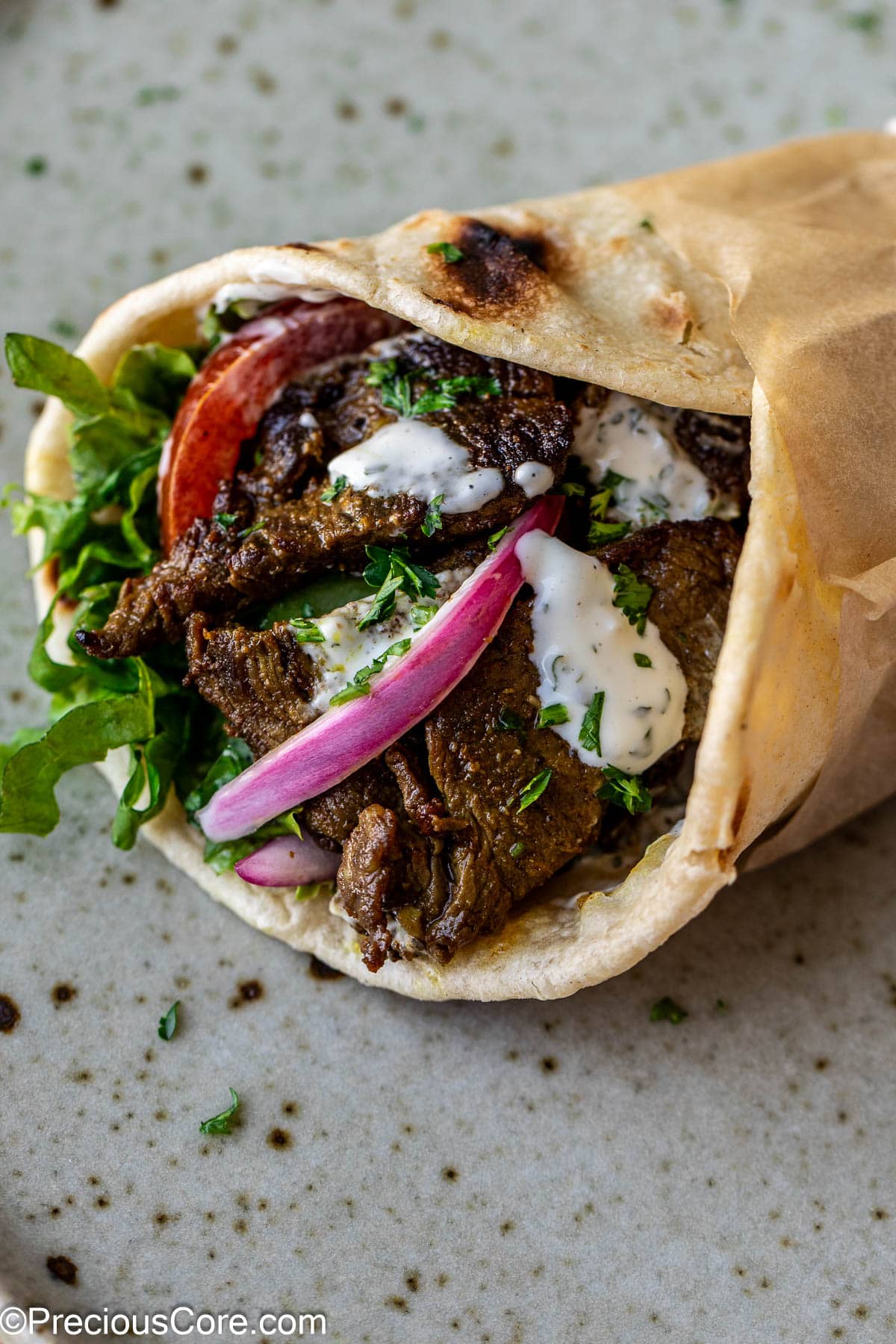 Beef shawarma wrap with veggies and sauce.