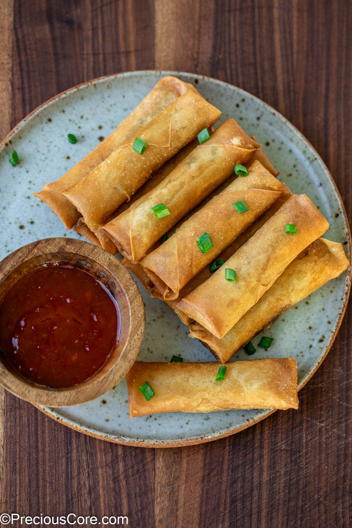 Chinese Spring Rolls on a plate swerved with sauce.