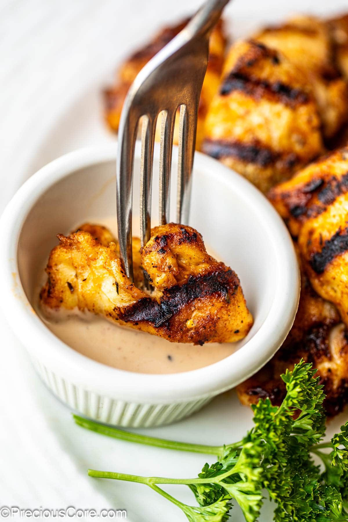 Dipping grilled chicken nuggets in sauce.