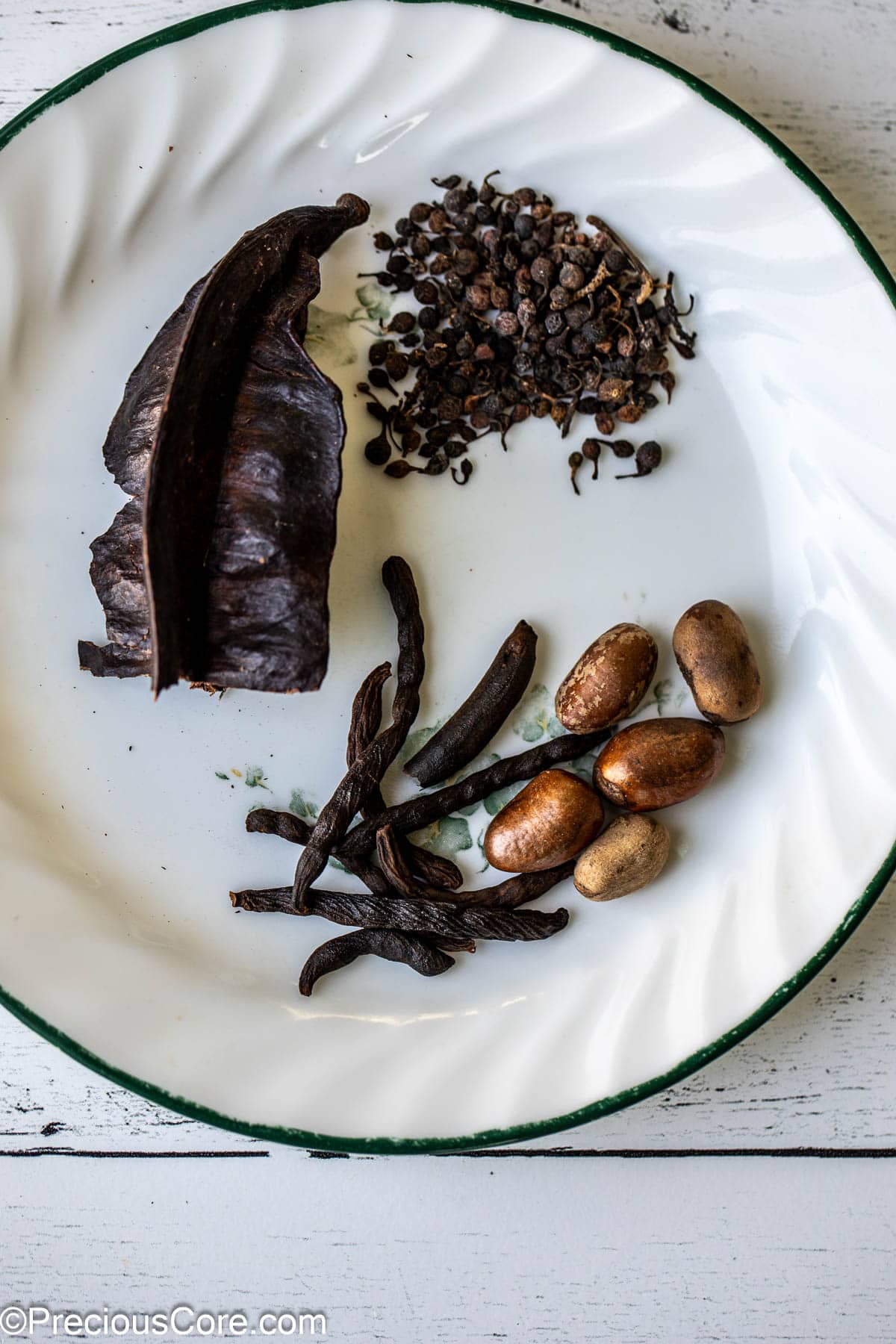 Aidan fruit, African black pepper, negro pepper, and African nutmeg on a white plate.