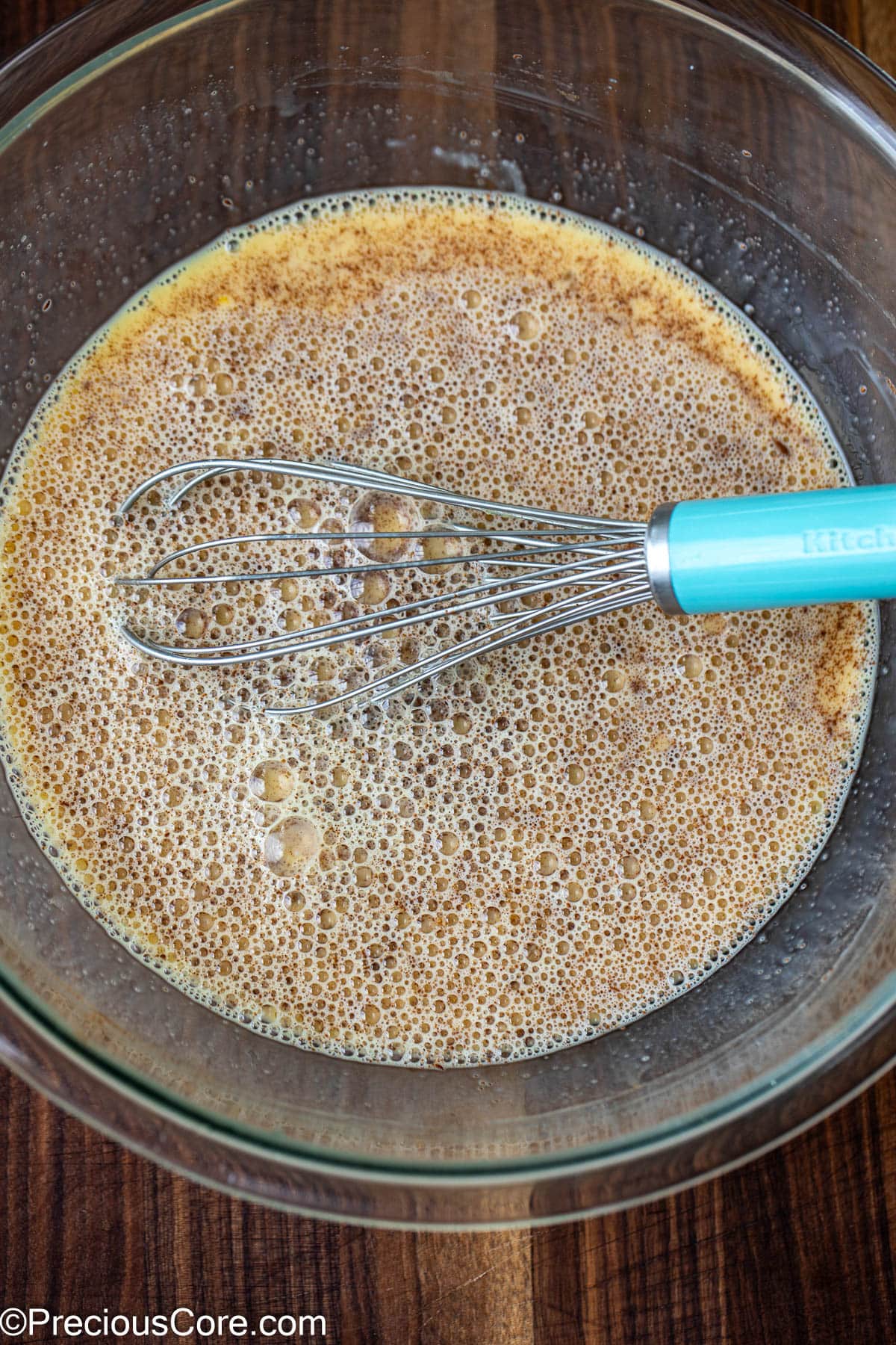 Eggs and milk mixture in a large bowl with a whisk.