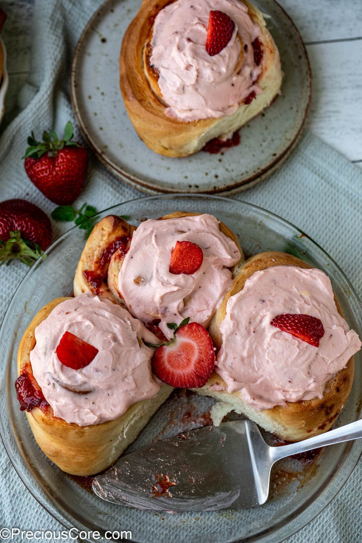 Plated strawberry cinnamon rolls with frosting.