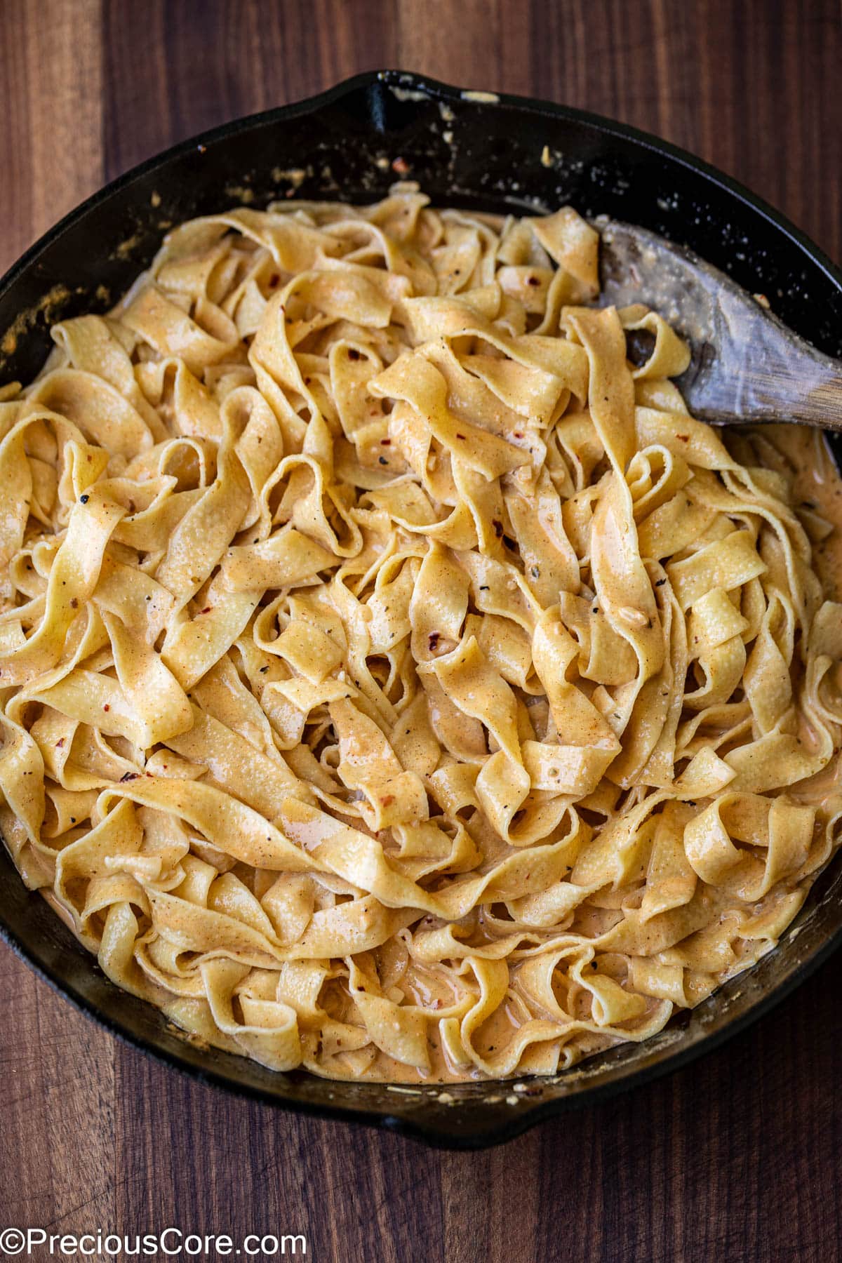 Mixing cooked pasta with homemade sauce.