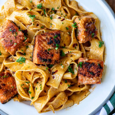 Cajun Pasta With Salmon plated with fresh herbs.