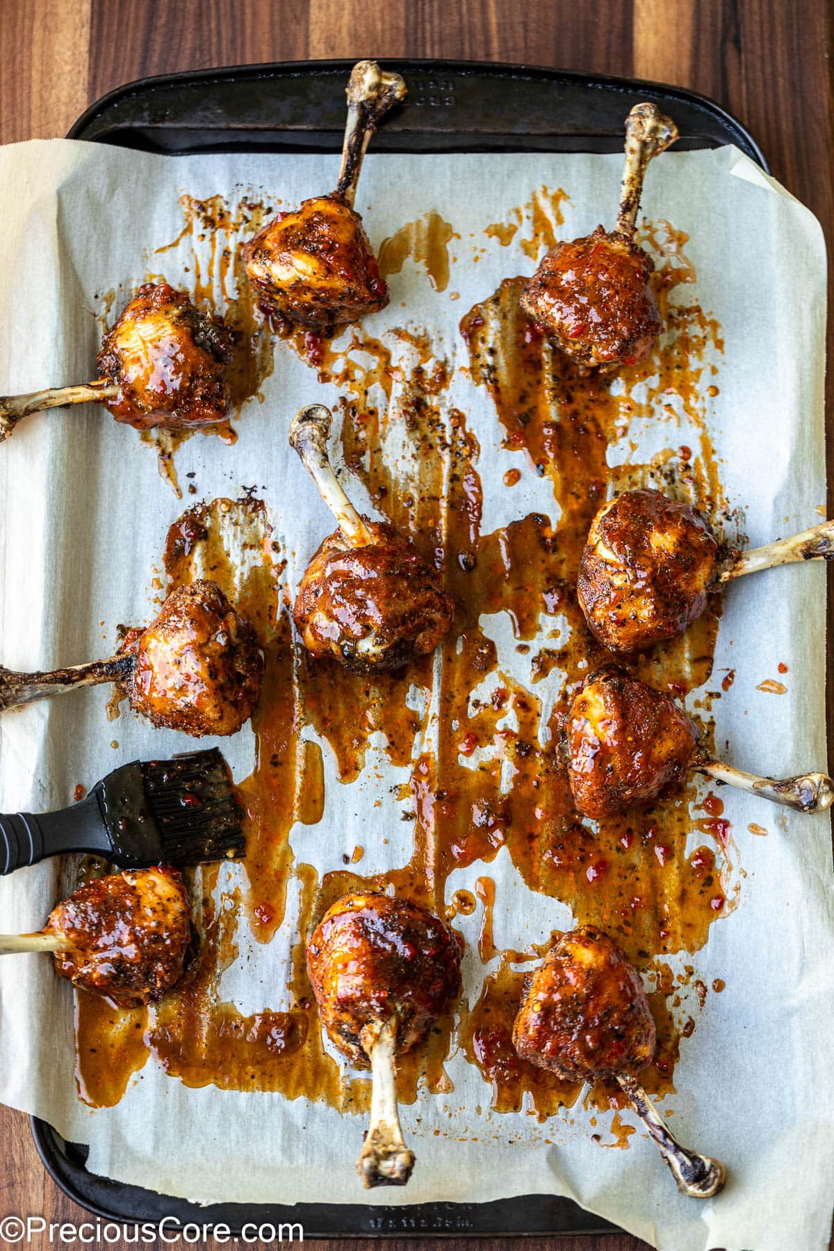 Brushing chicken lollipops with sauce.