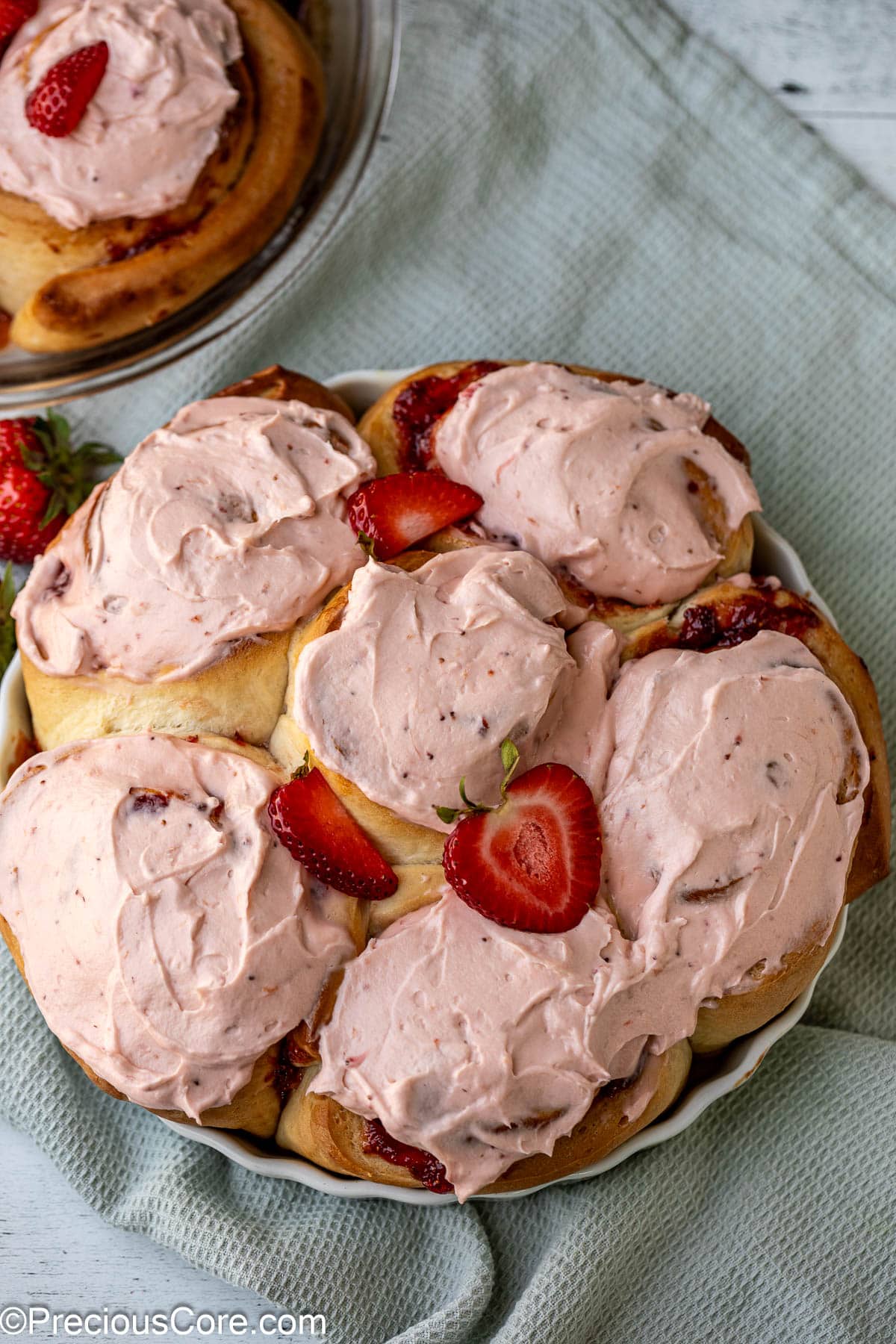 Frosted strawberry cinnamon rolls in round baking dish.