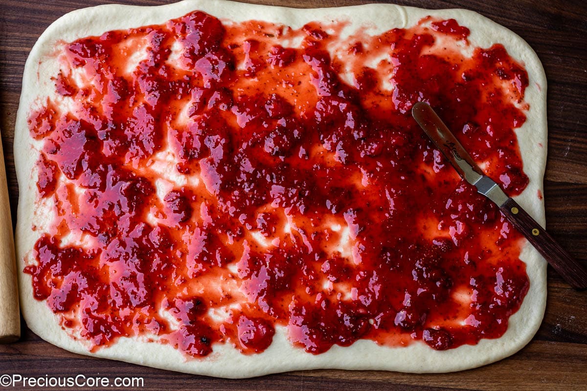 Strawberry compote spread on rolled-out dough.