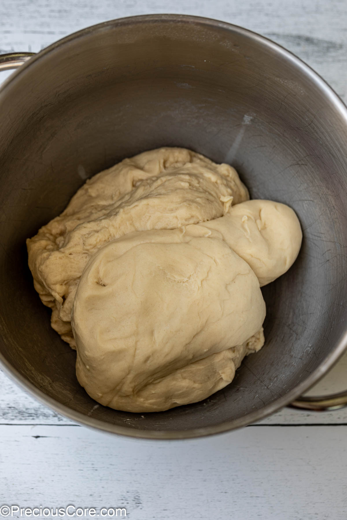 Soft cinnamon roll dough in a metal bowl.