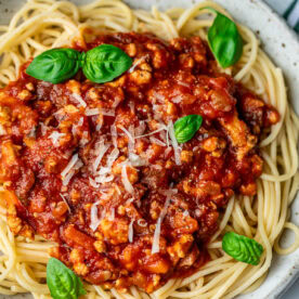 Spaghetti in a bowl topped with chicken Bolognese sauce.