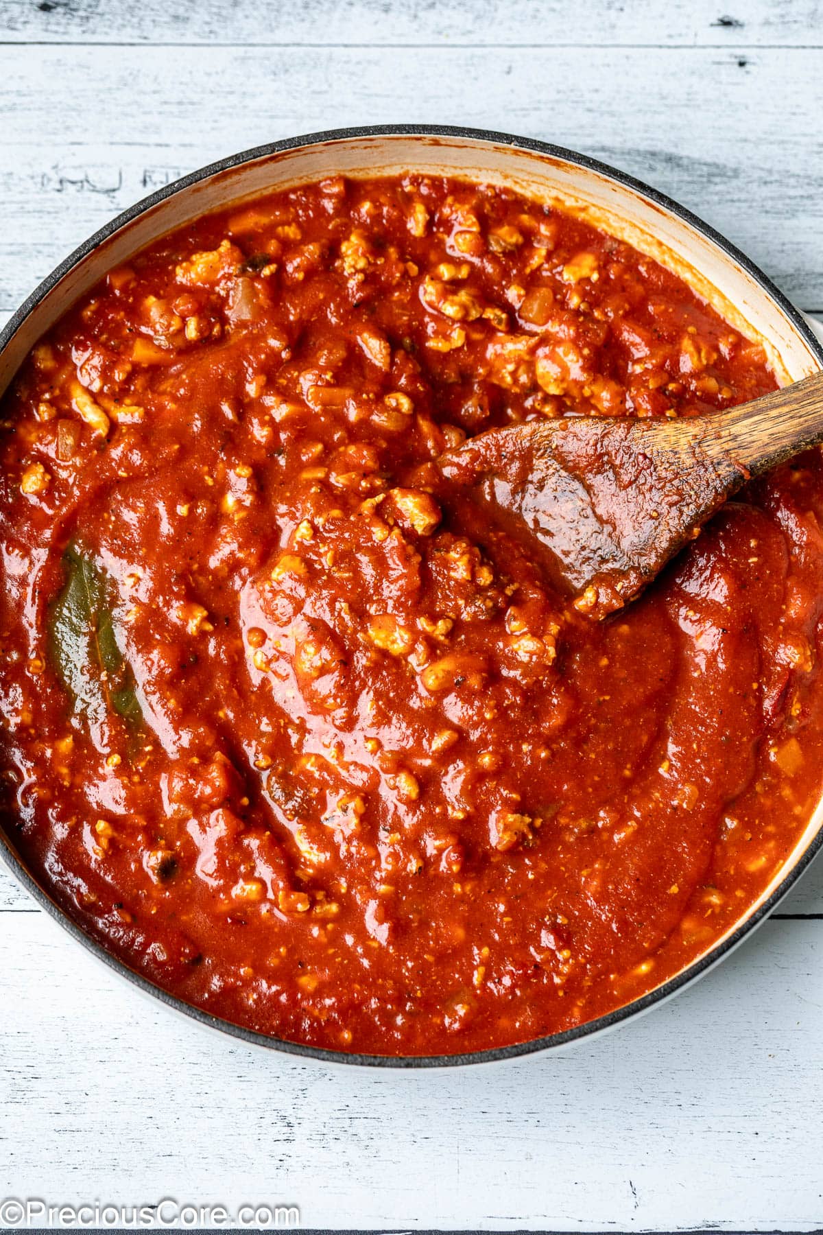 A pot of vibrant red sauce made with chicken.