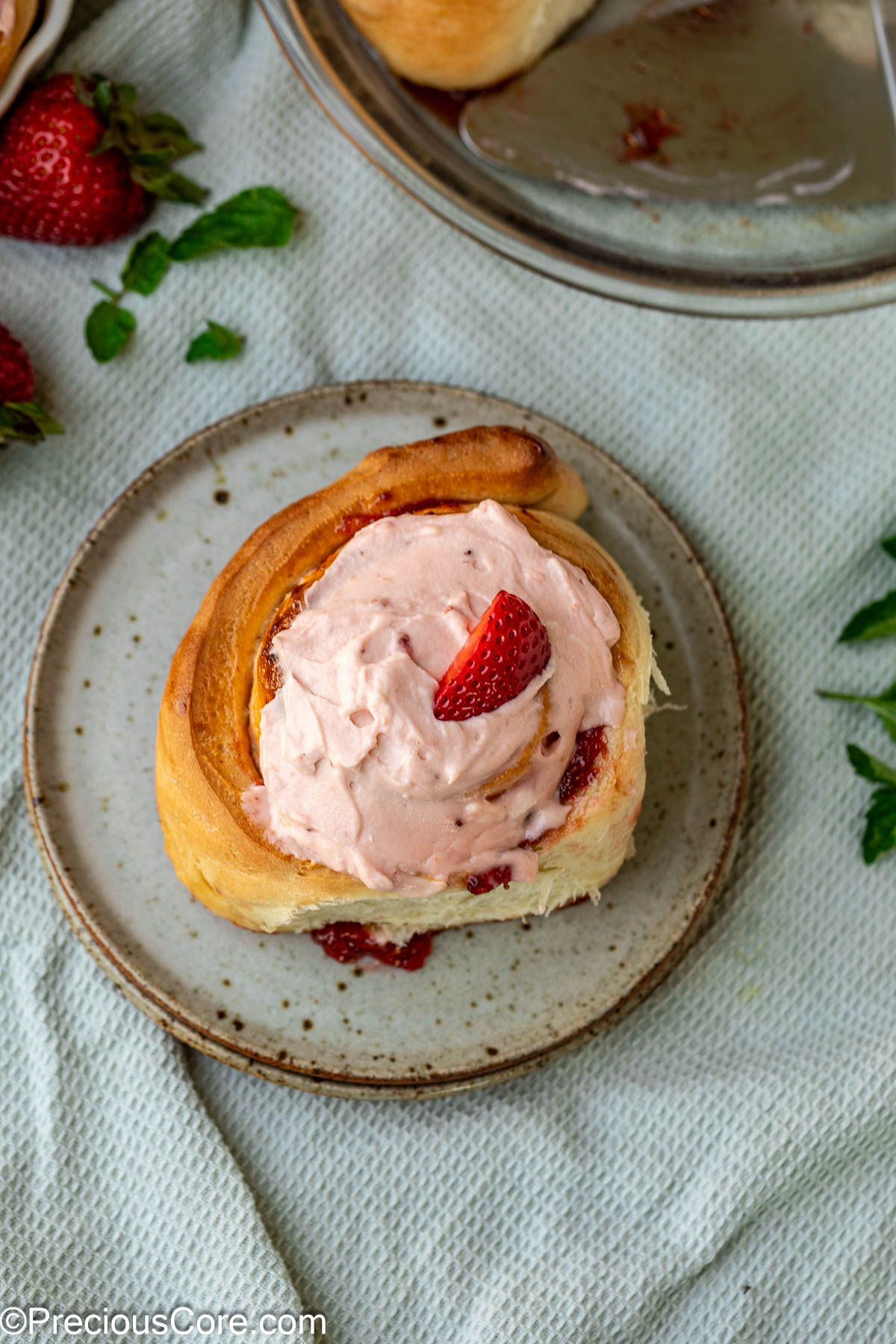 A strawberry cinnamon roll on a dessert plate.