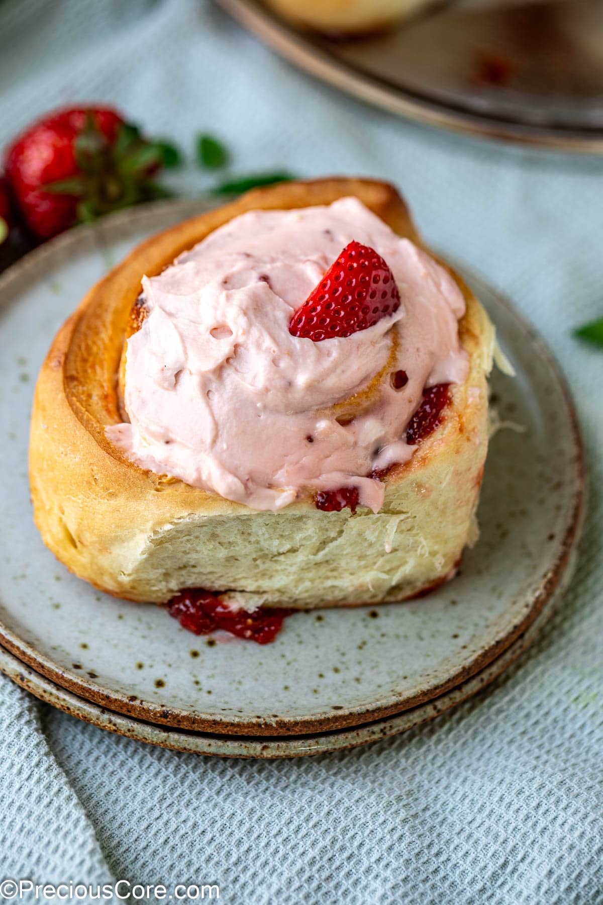 Strawberry cinnamon roll with fresh strawberry garnish.