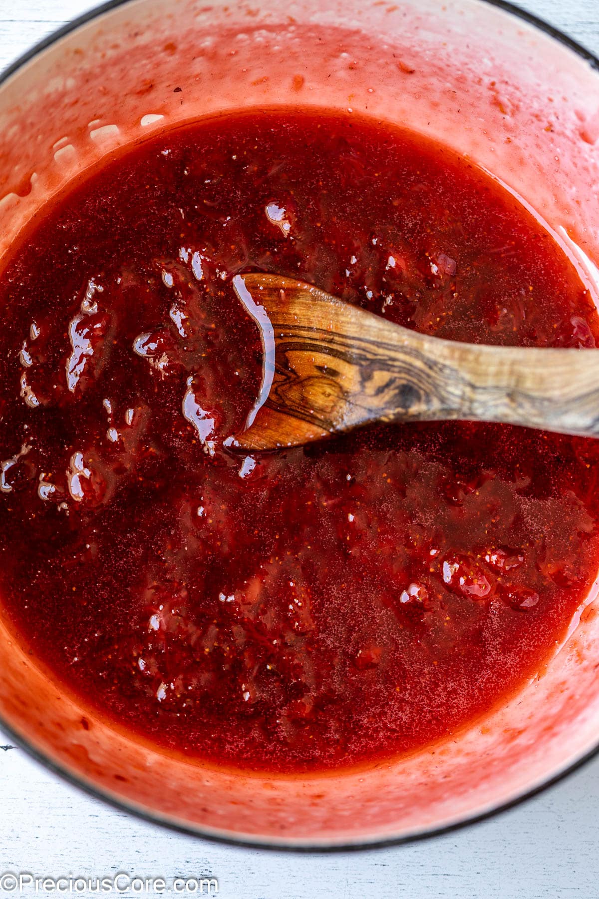 Mixing strawberry compote with a wooden spoon.