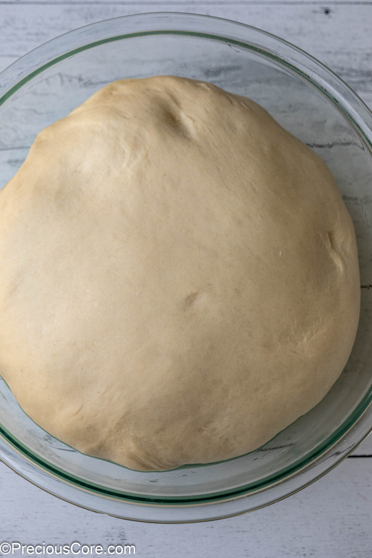 Risen cinnamon roll dough in a bowl.