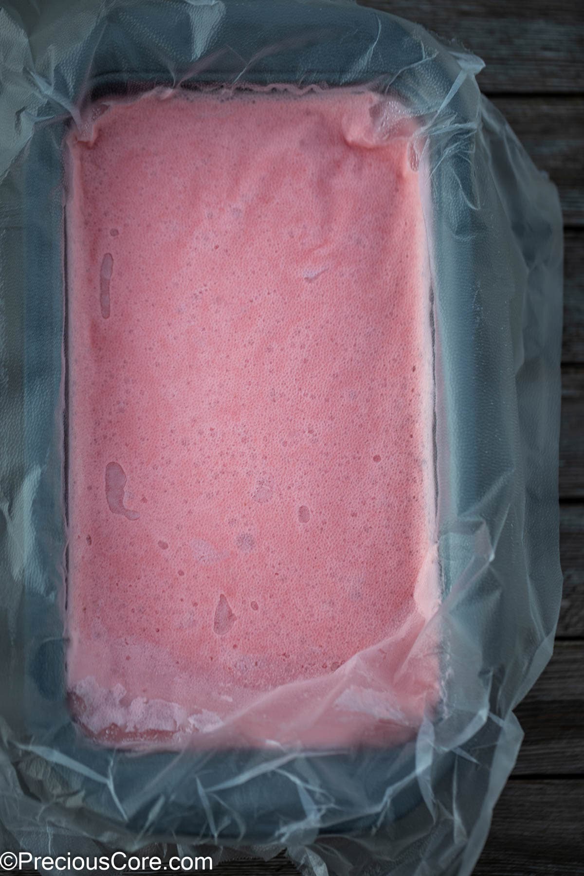 Plastic covering watermelon ice cream mixture.