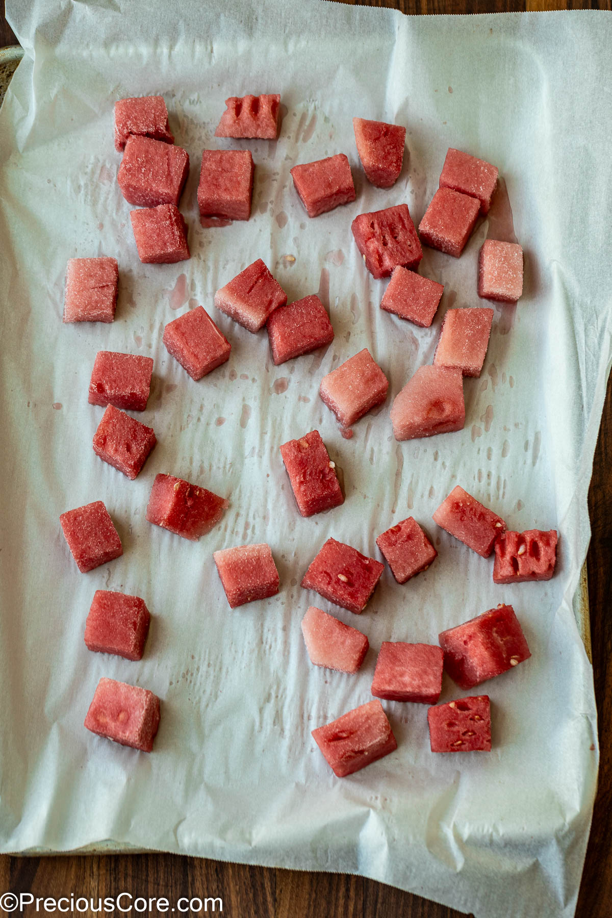 Watermelon cubes on a parchment-lined sheet pan.