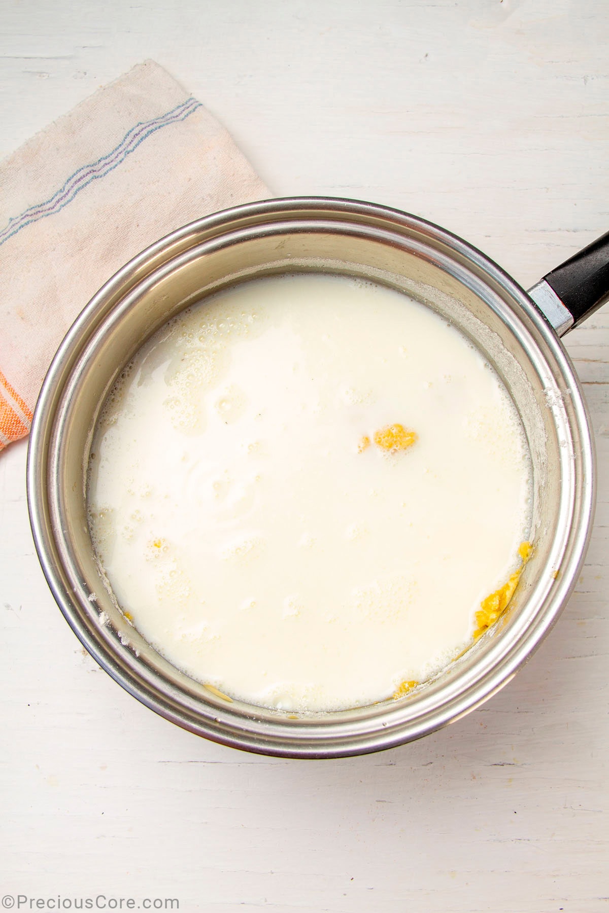 Milk added to a roux in a saucepan.