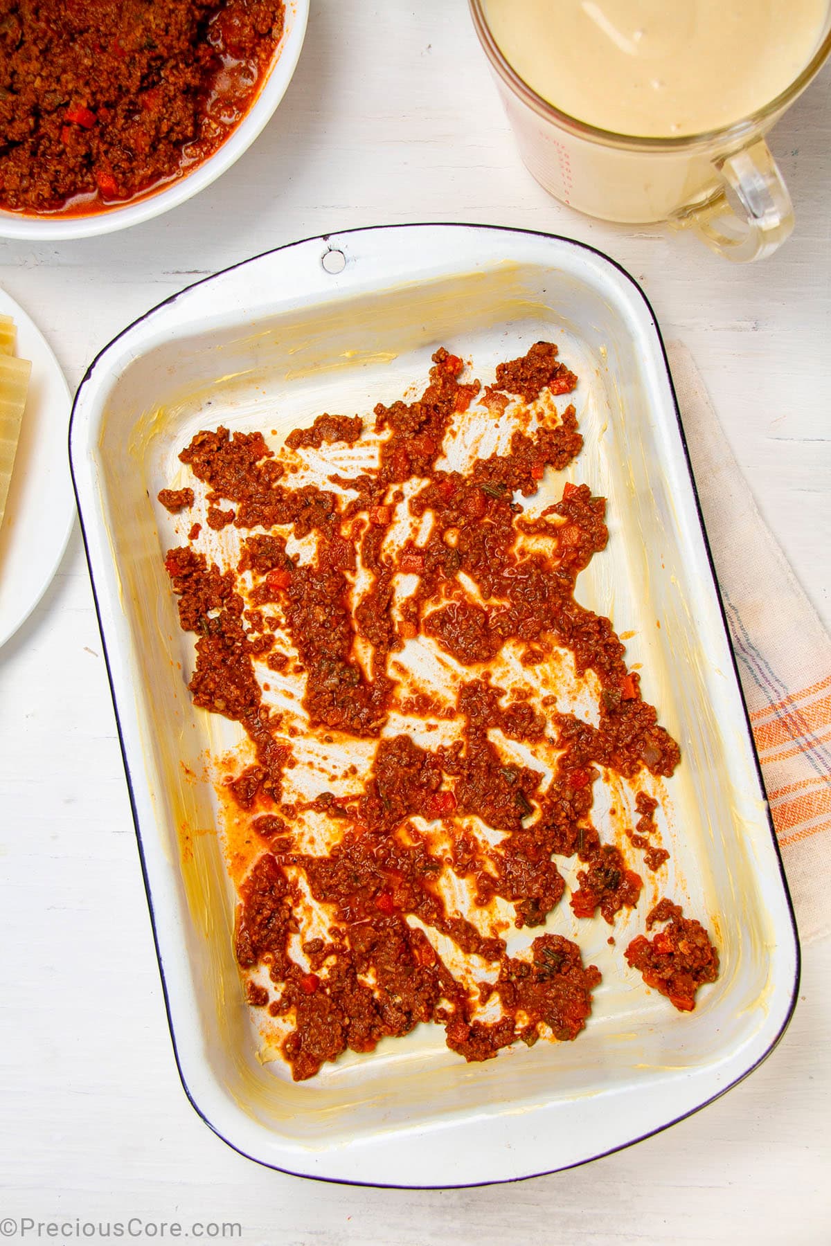 Meat sauce spread on the bottom of a baking dish.