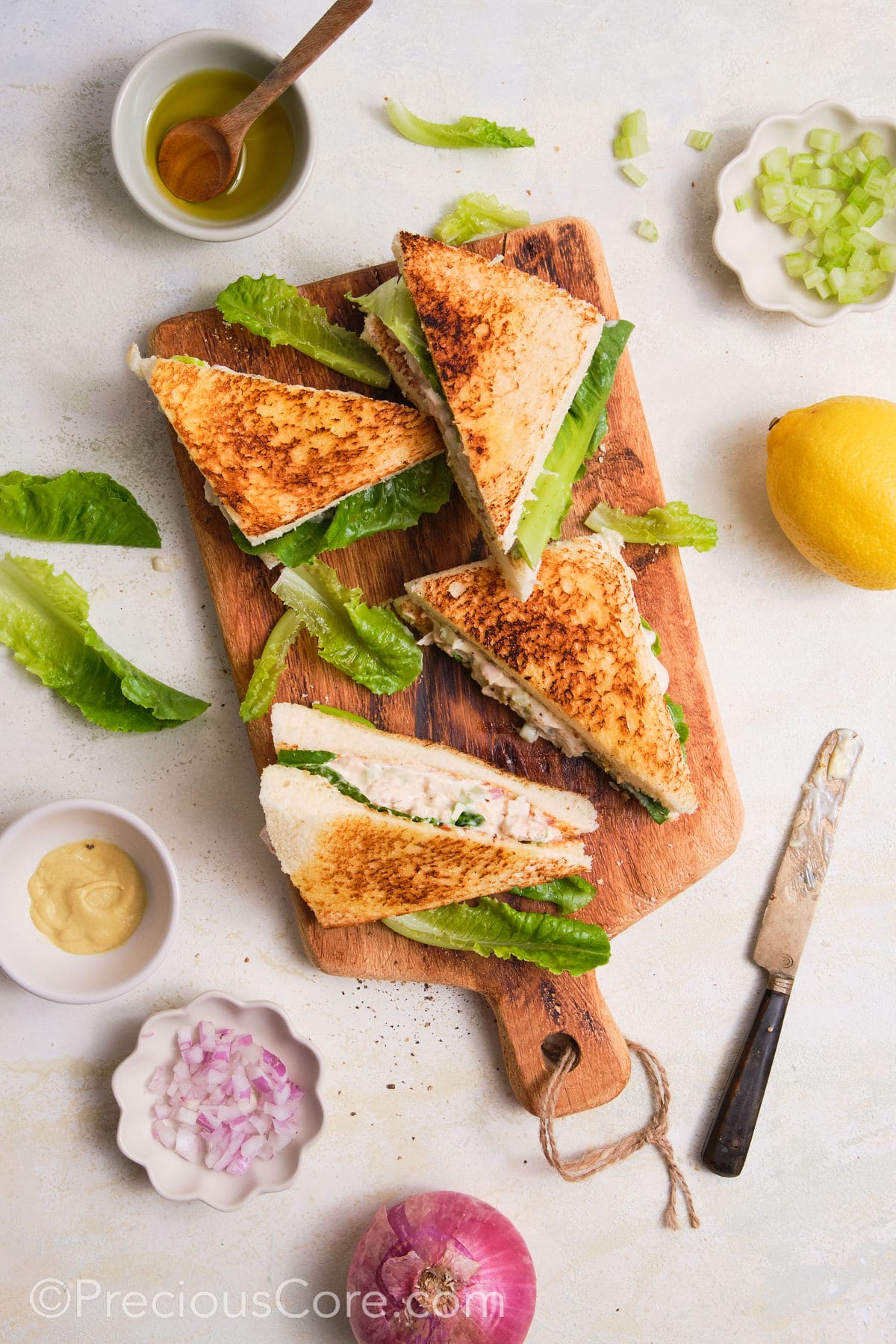 Cut chicken mayonnaise sandwiches on a cutting board.