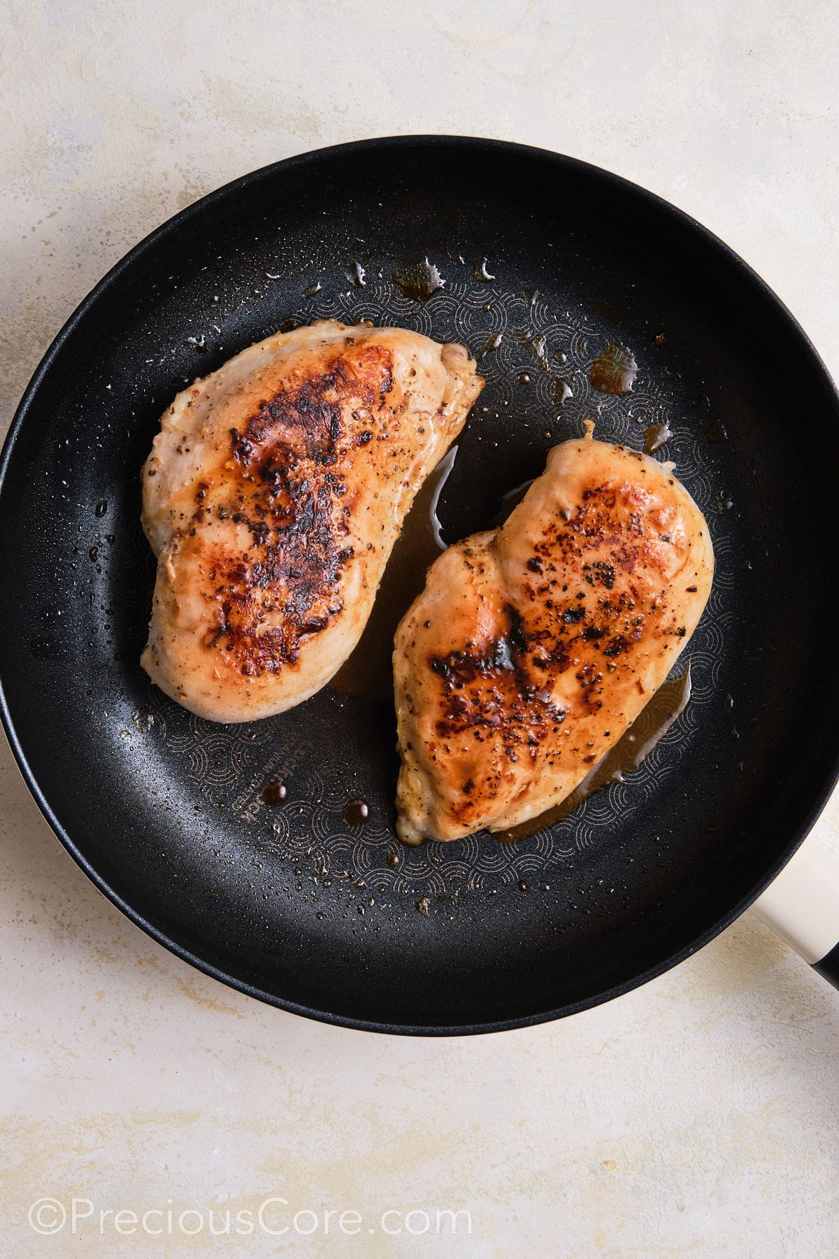 Searing chicken breasts in a skillet.