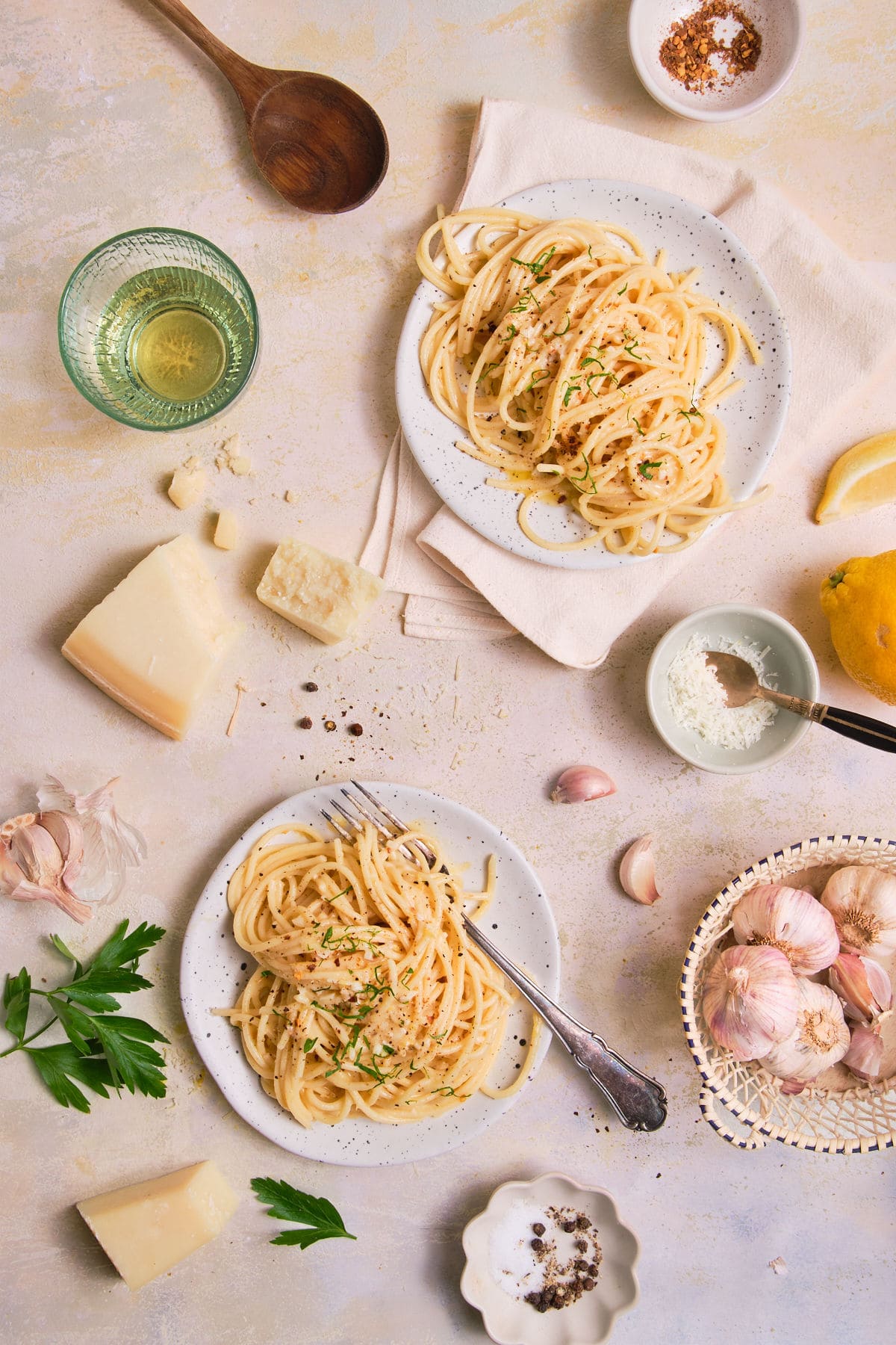 2 plates of swirled spaghetti garnished with parsley and black pepper.