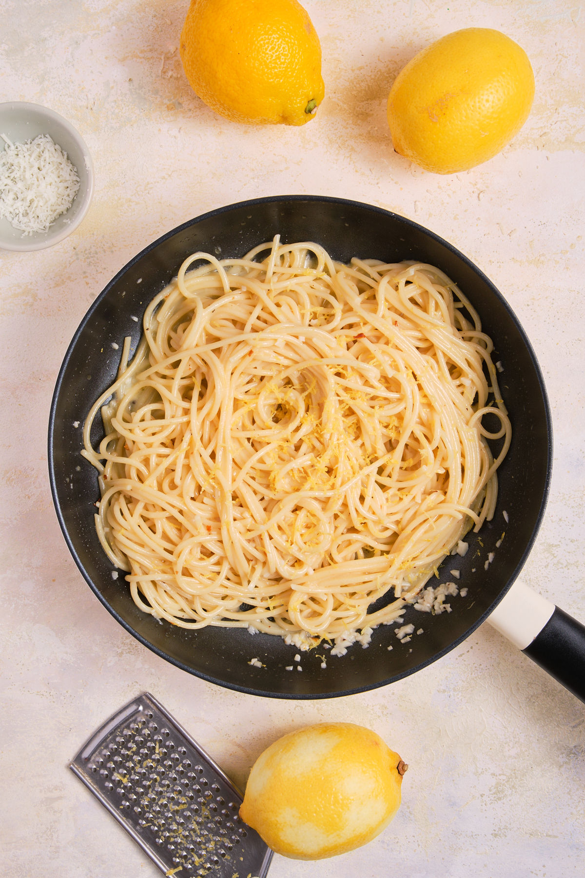 Lemon zest added to a pan of pasta.