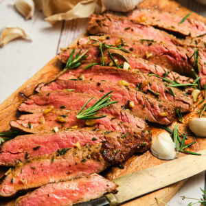 Sliced pan seared flank steak on a cutting board.