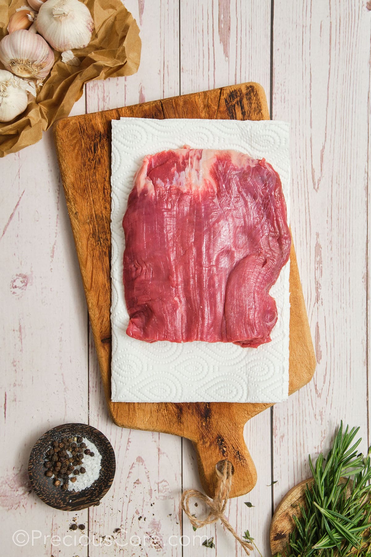 Patting dry flank steak with paper towels.