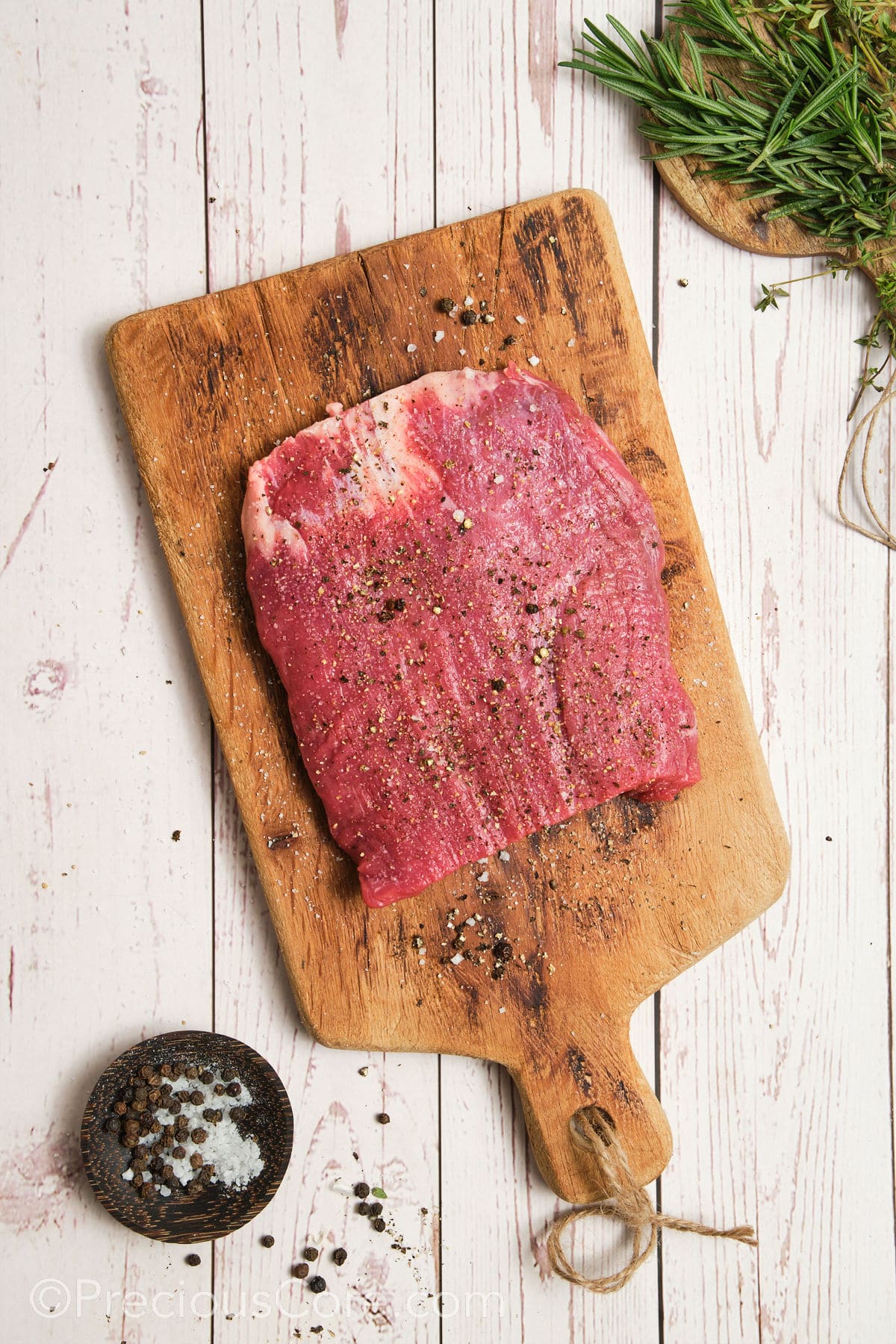 Seasoning flank steak with salt and pepper.