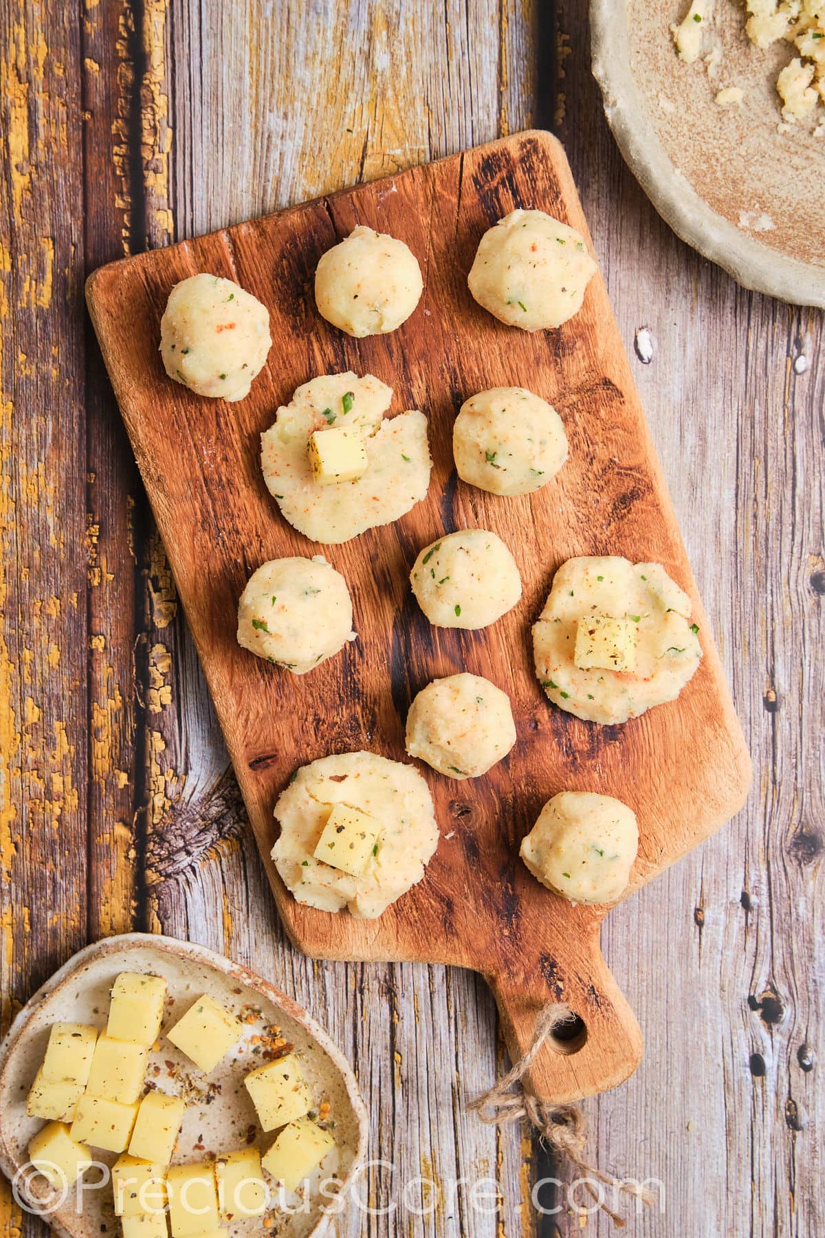 Adding cheese cubes to mashed potato balls.