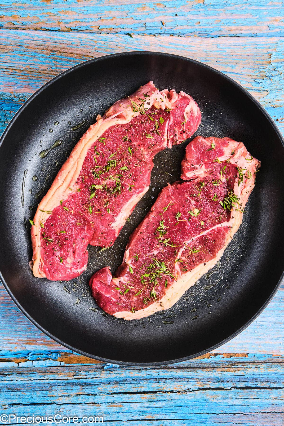 Seasoned steaks in a non-stick skillet.