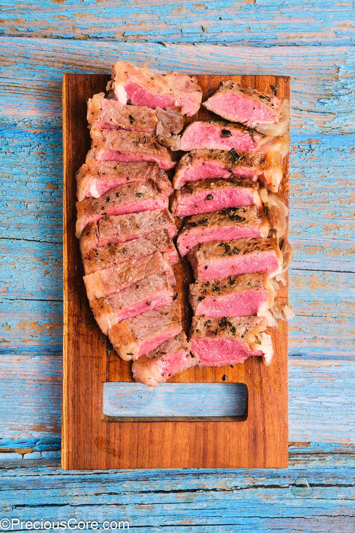 Cooked sliced ribeye steak on a chopping board.