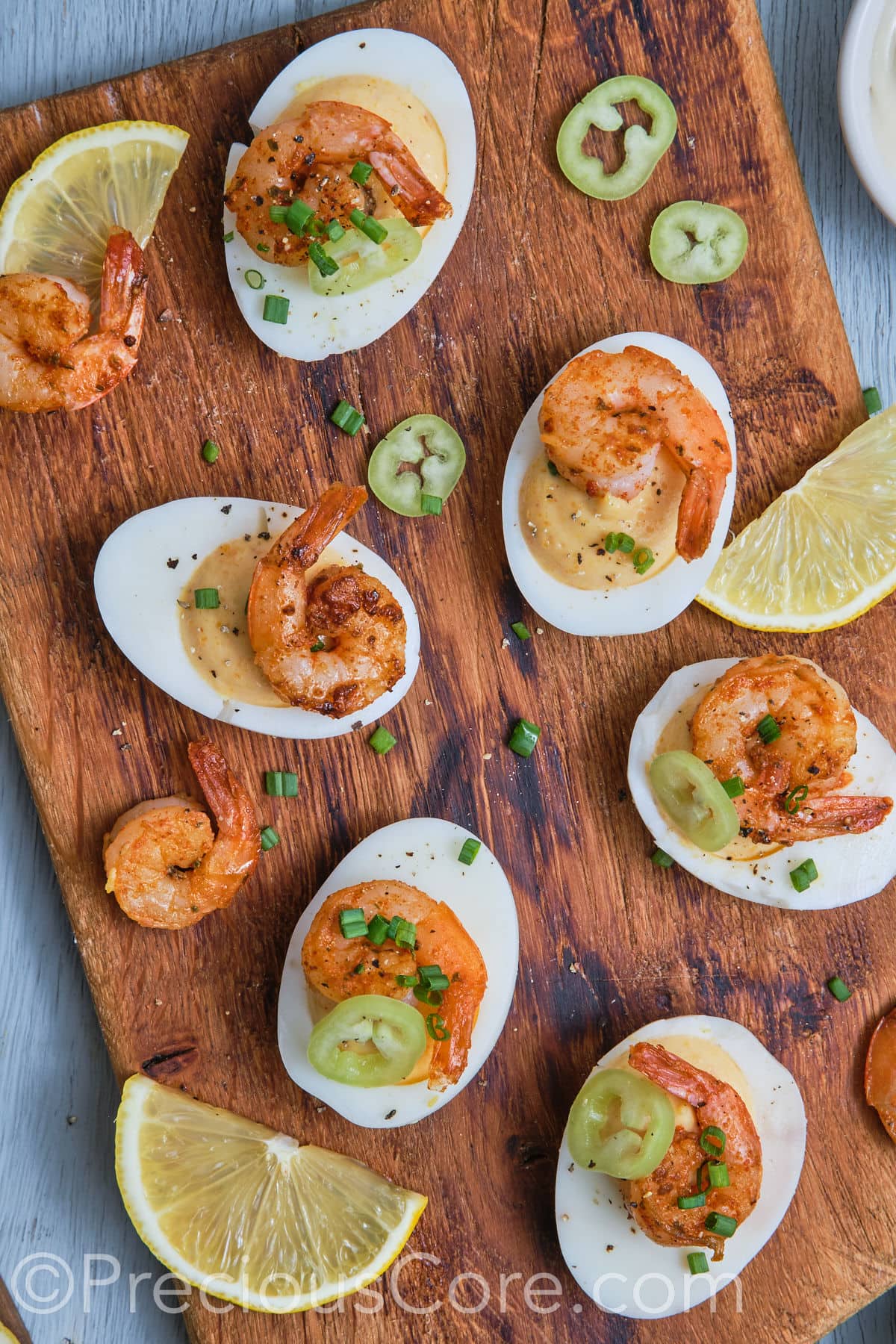 Deviled eggs with shrimp on a chopping board. 