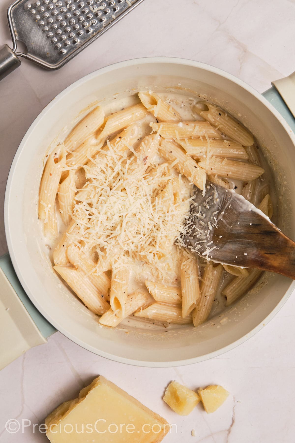 Parmesan added to the pot of creamy pasta.