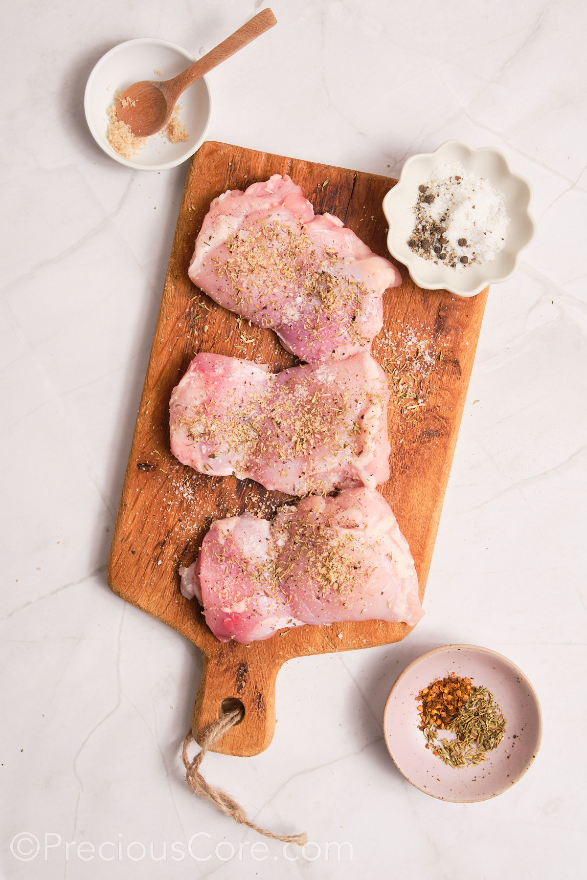 Seasoning chicken on a chopping board.