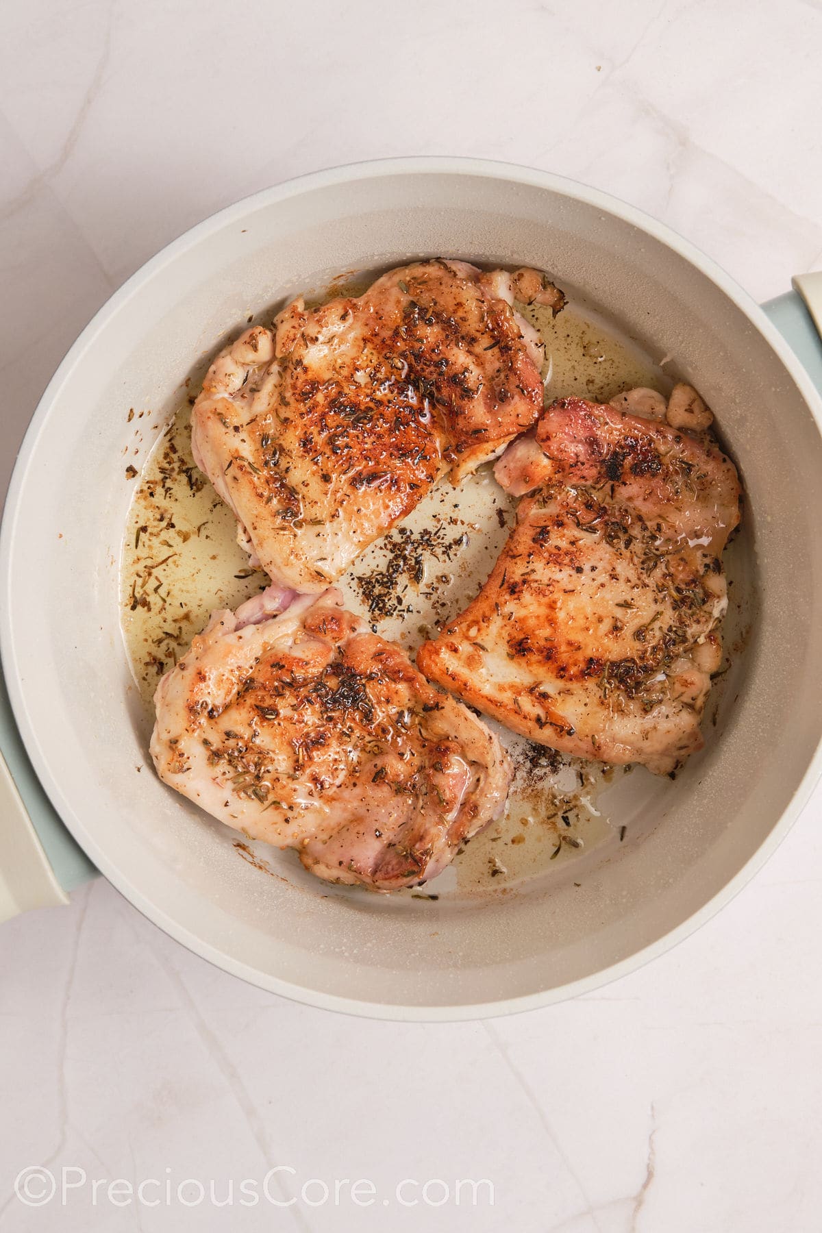 Browned chicken thighs in a pot.