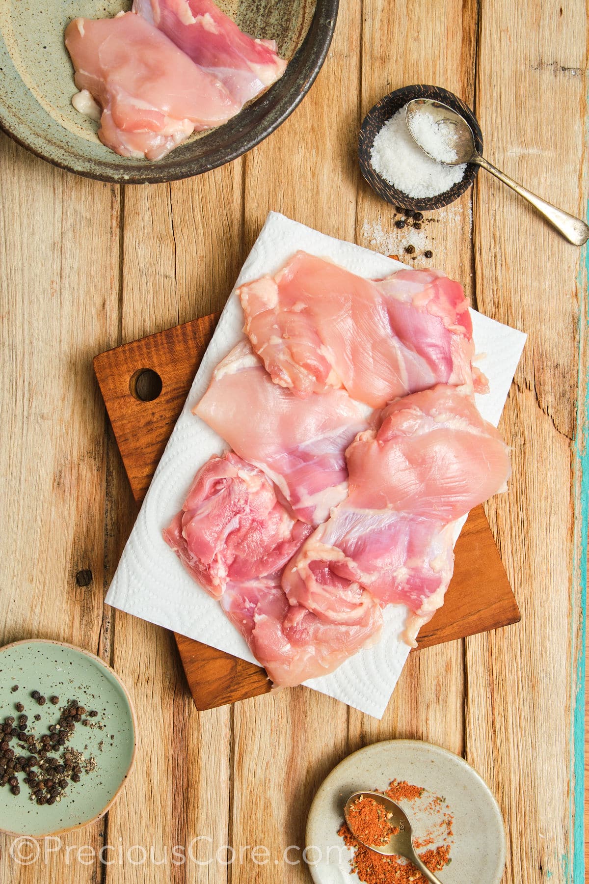 Patting chicken thighs dry with paper towels.