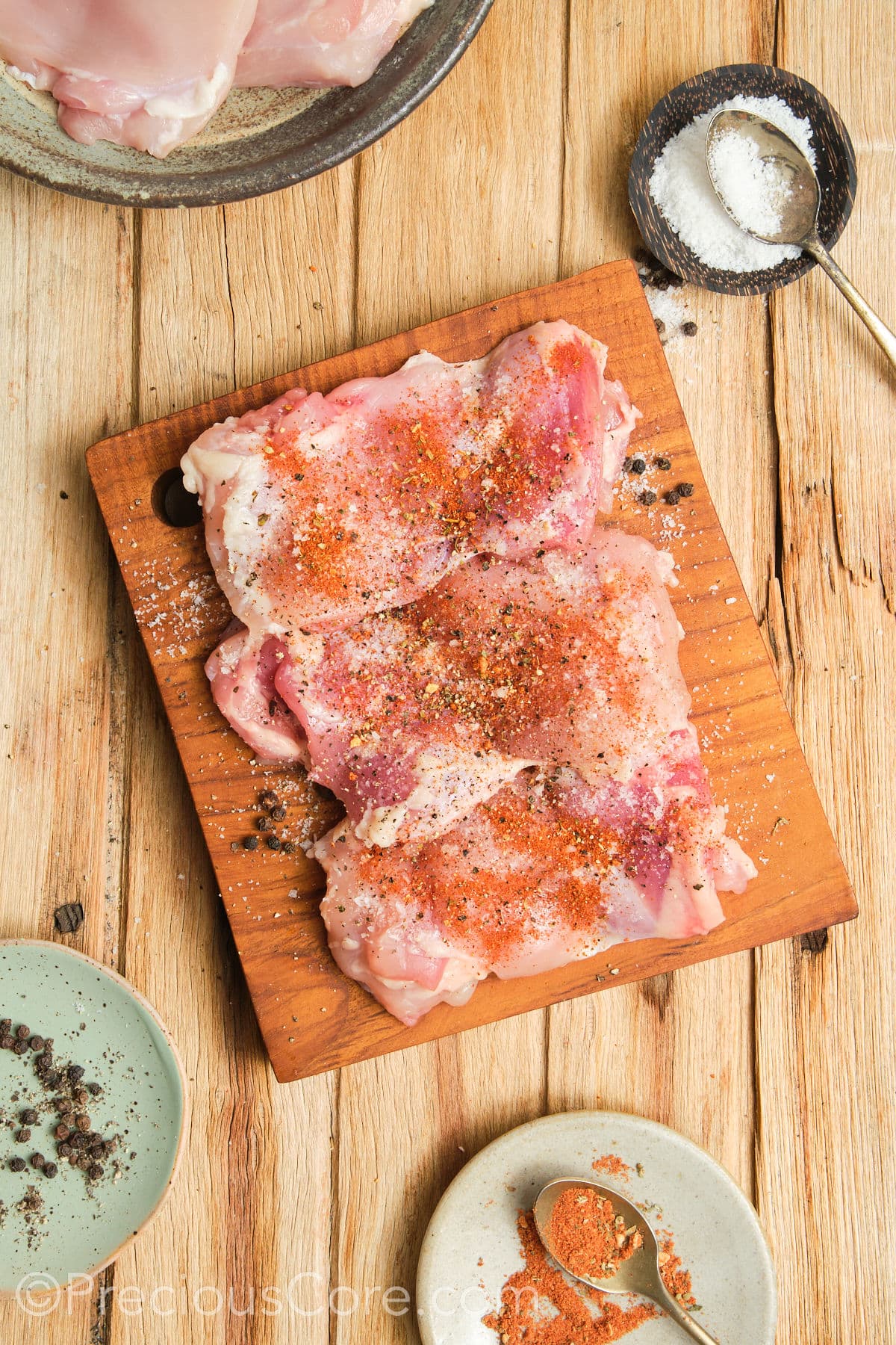 Seasoning chicken thighs with dried spices.