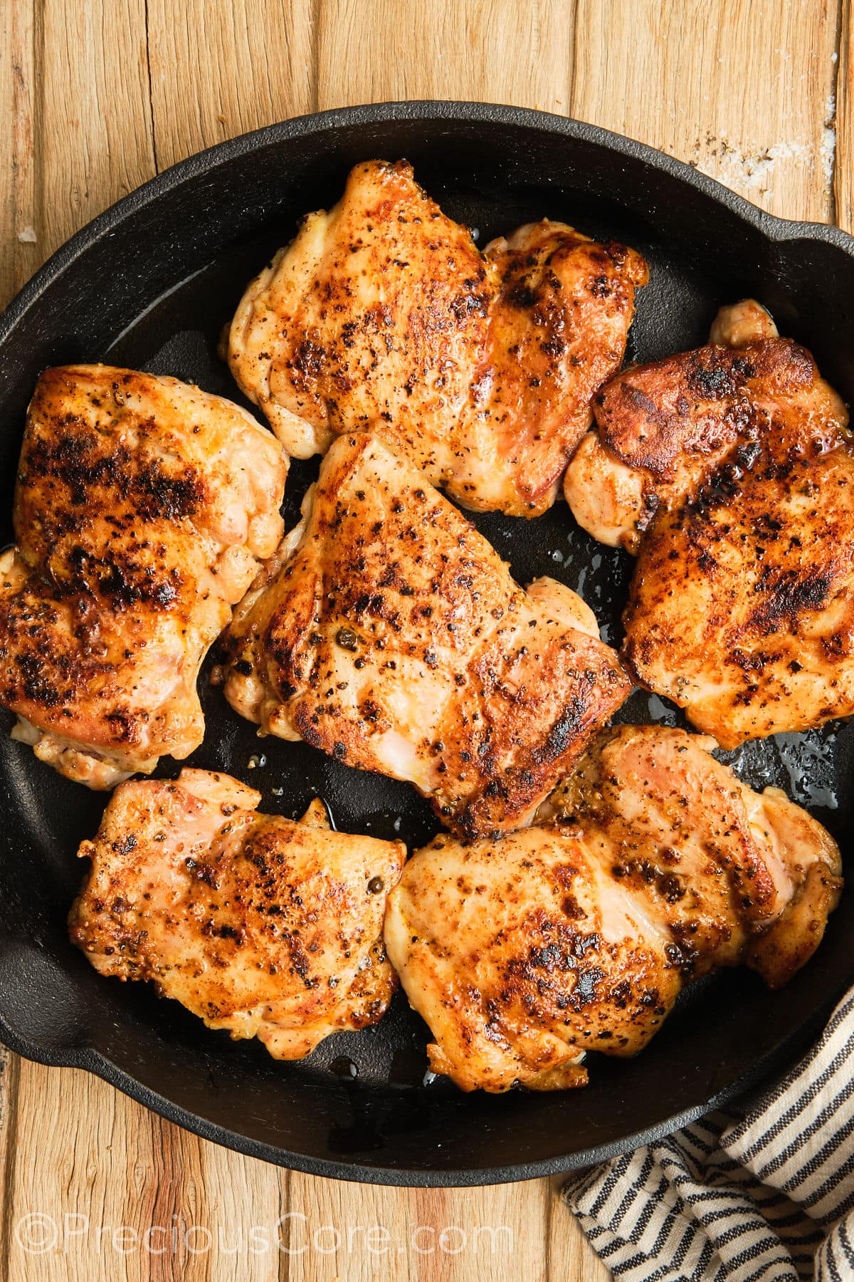 Seared boneless chicken thighs in a skillet.