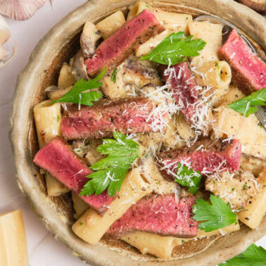 Square image of steak and mushroom pasta.