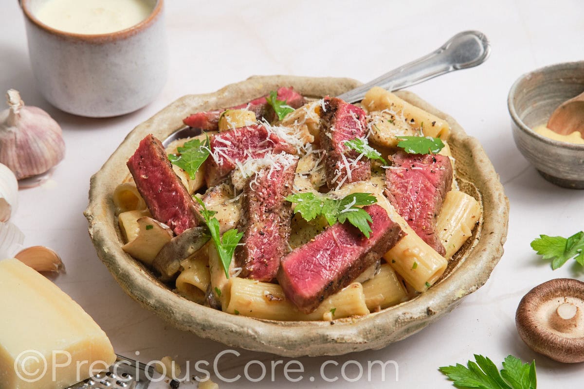 Landscape photo of steak and mushroom pasta.