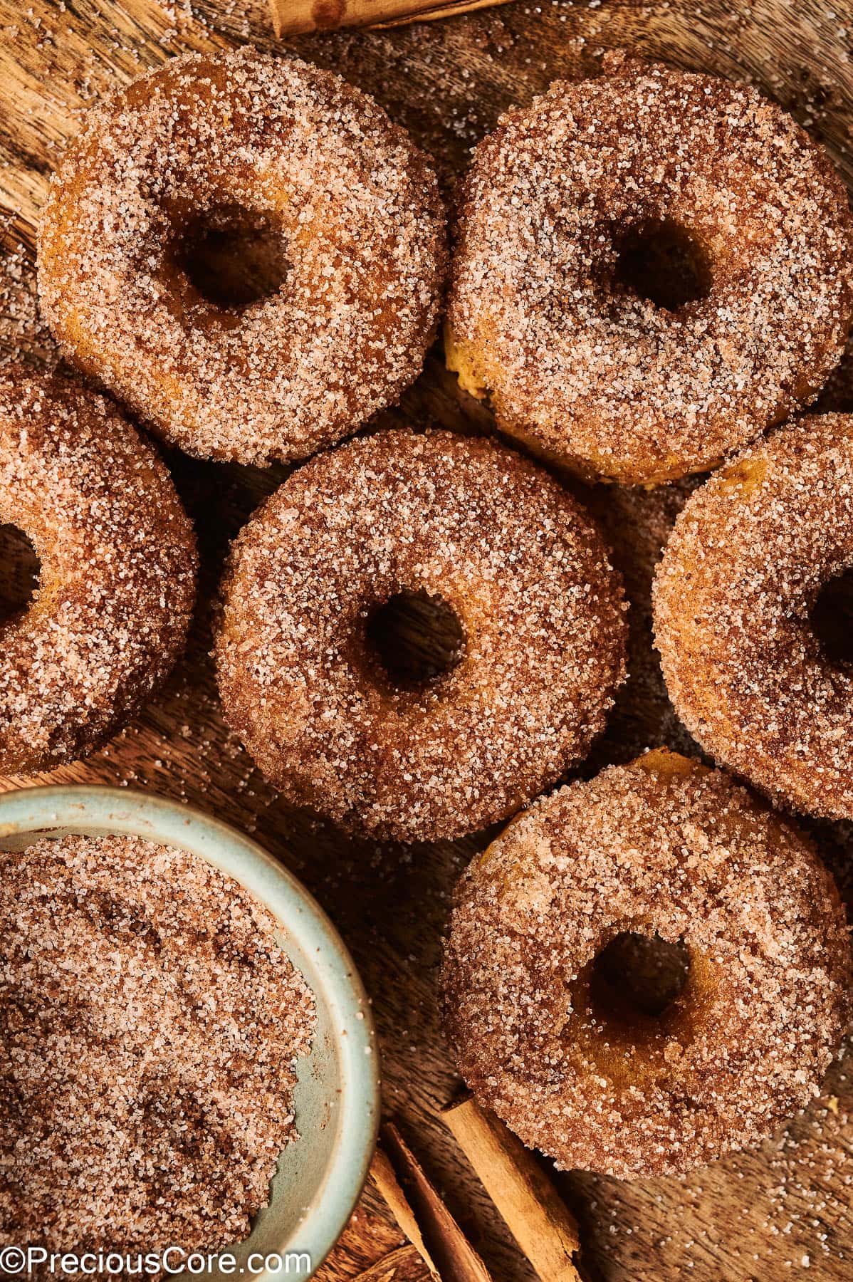 Cinnamon sugar pumpkin doughnuts on a wooden board.