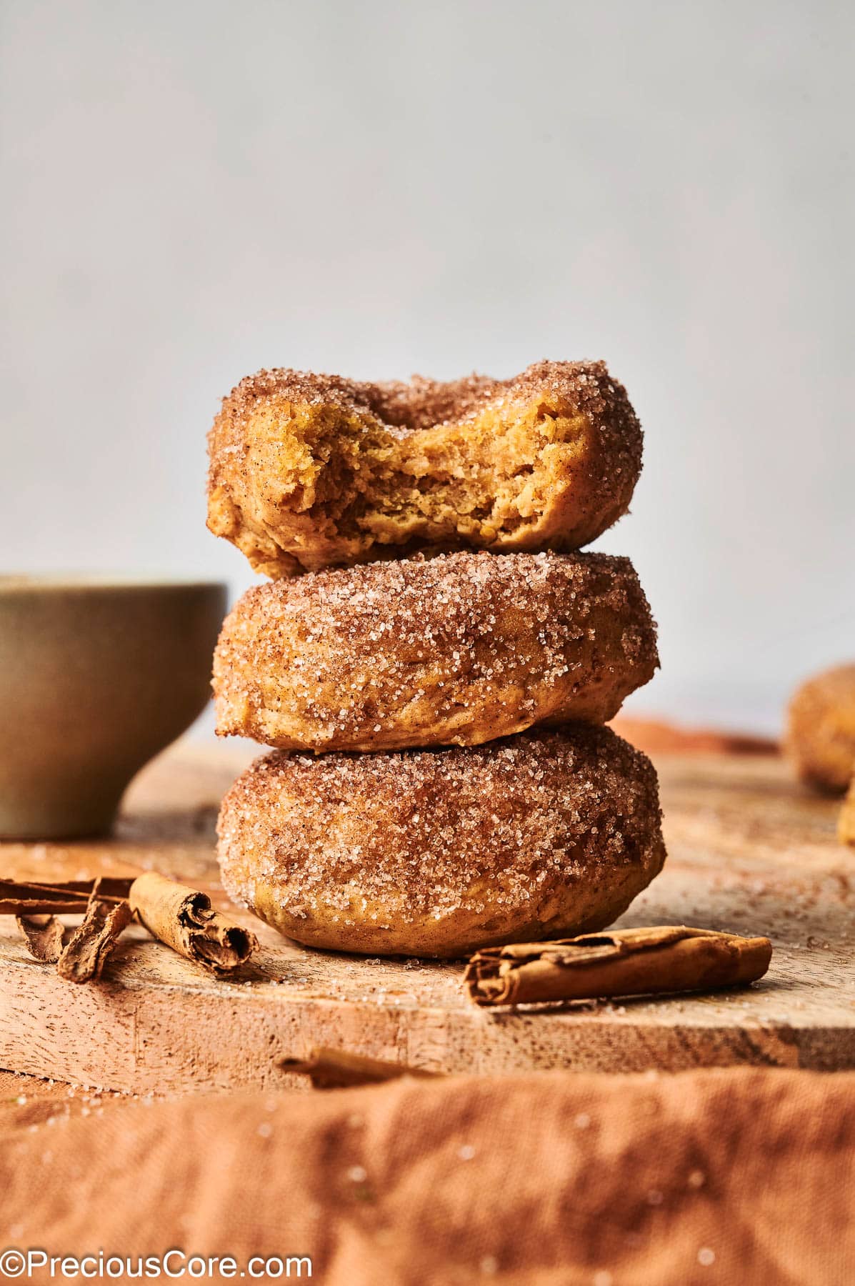 Cinnamon sugar pumpkin doughnuts with a bite taken out of one.