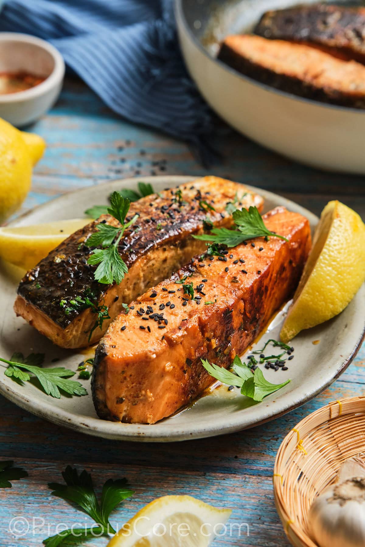 2 cooked salmon fillets garnished with black sesame seeds.