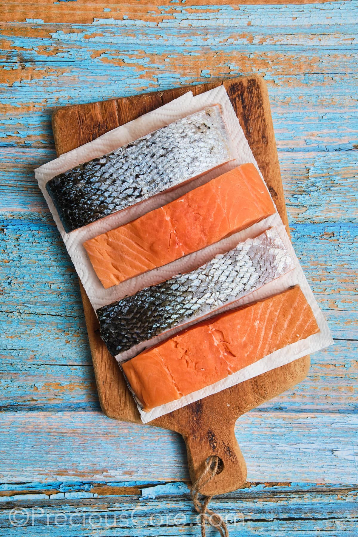 Patting salmon dry with paper towels.