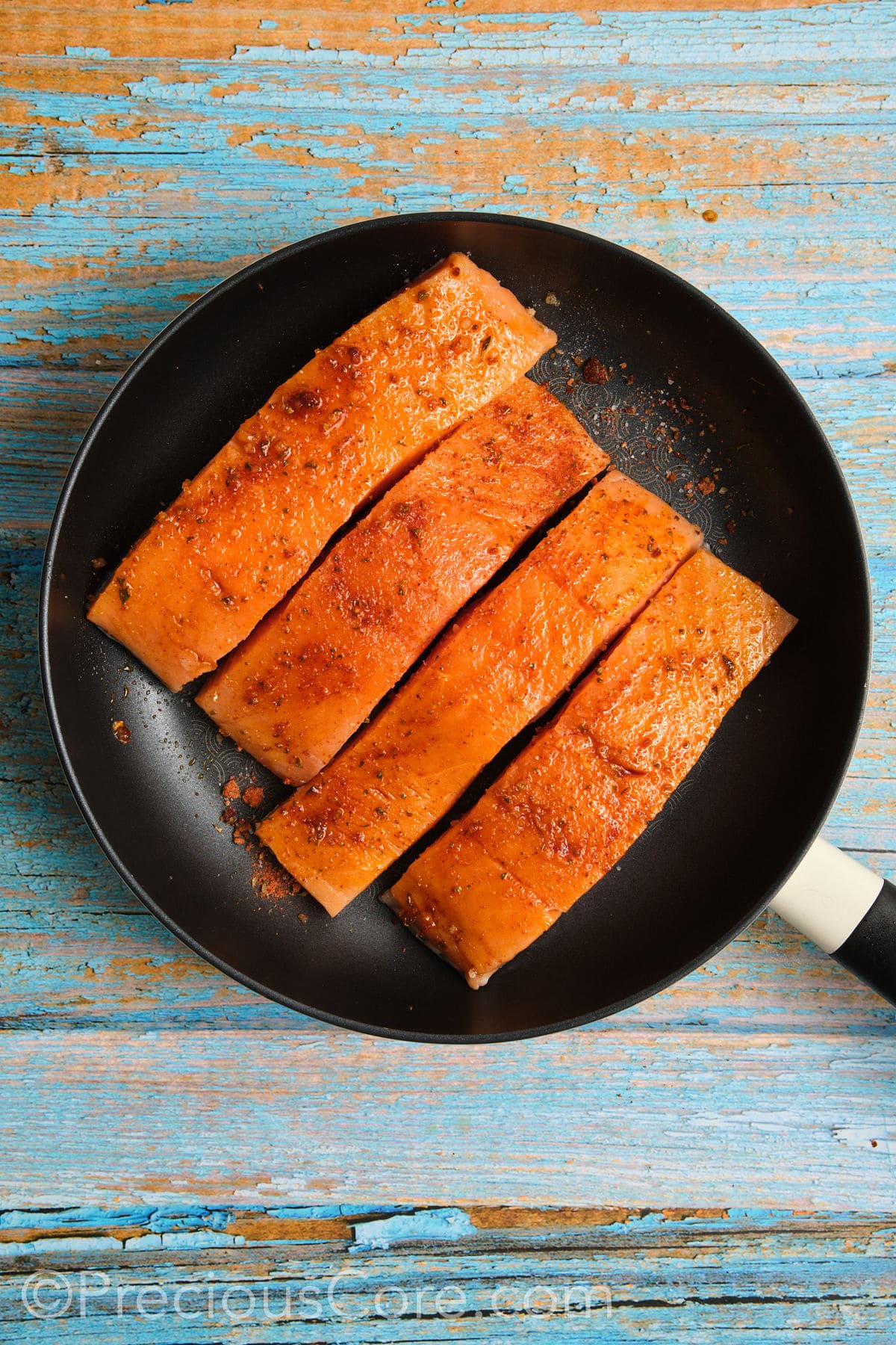 Salmon cooking in a skillet.